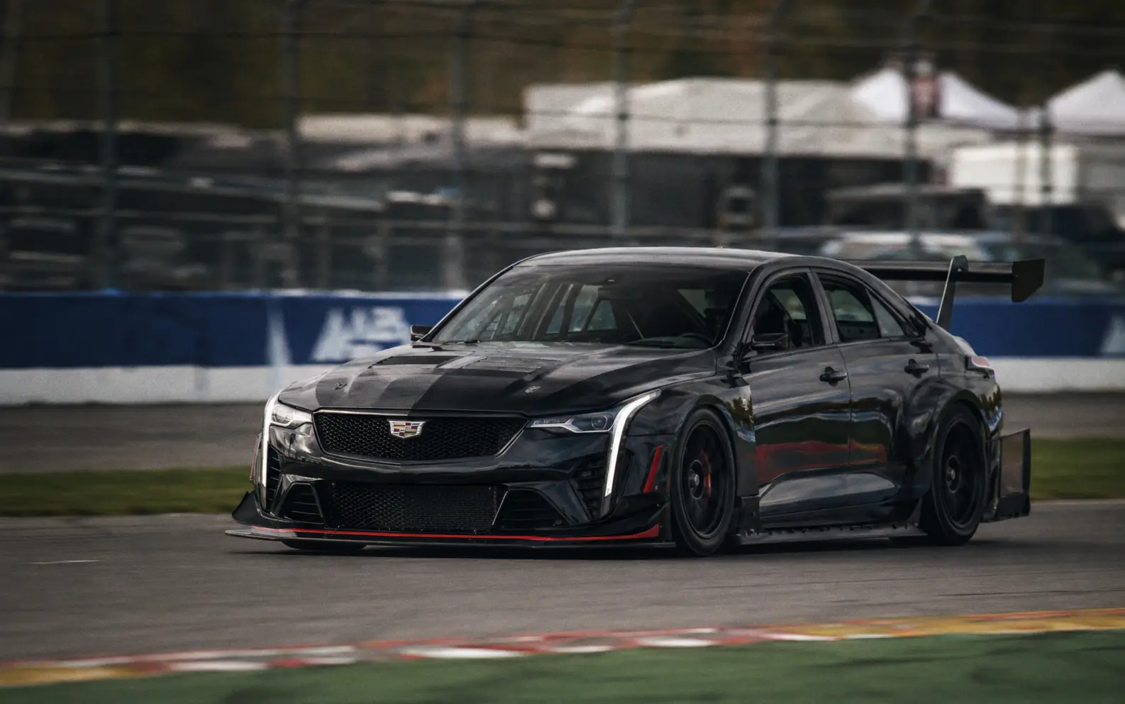 Cadillac CT4-V Blackwing race car with a large front splitter and rear wing on track